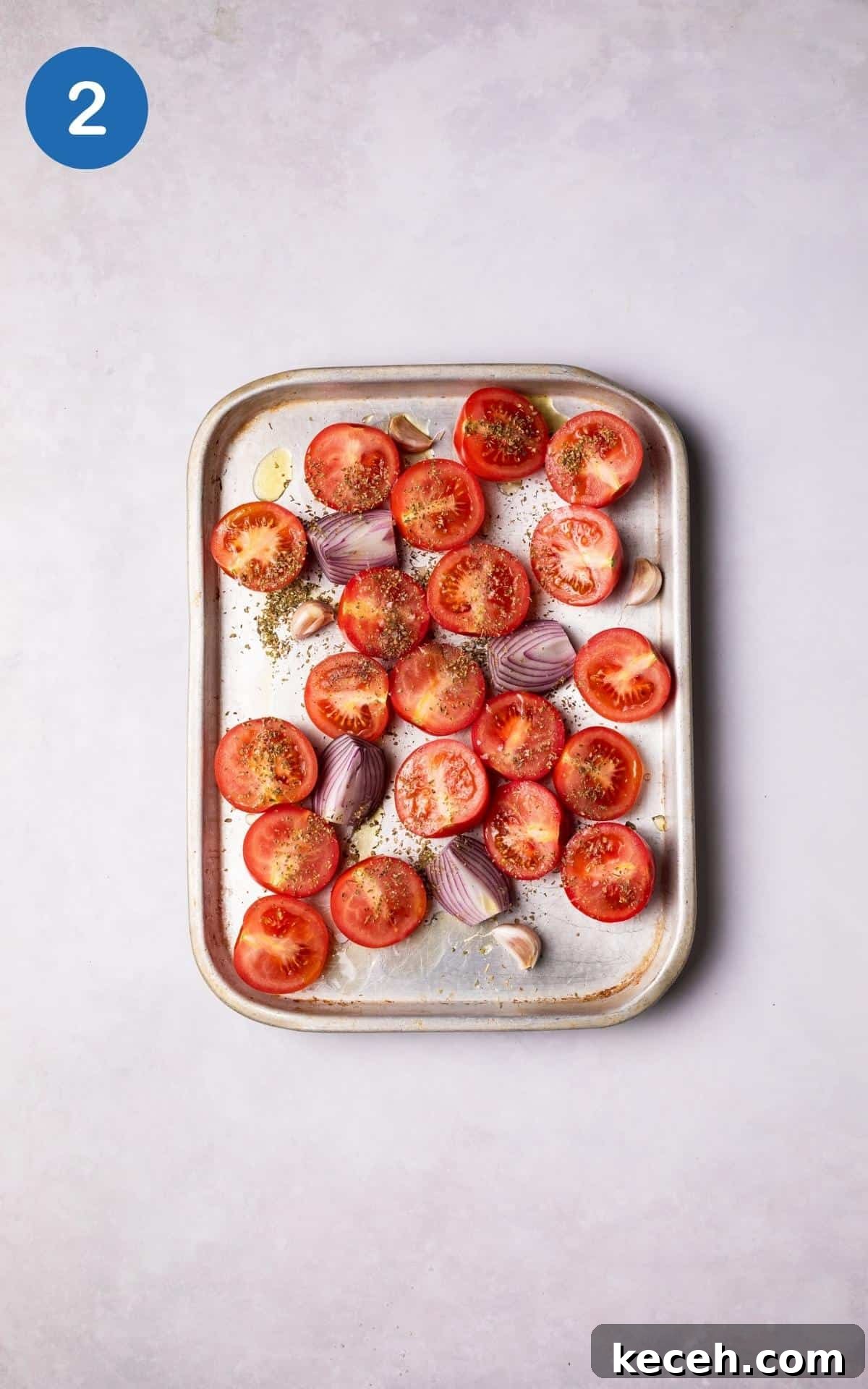 Creamy Roasted Tomato Soup Recipe with Garlic and Basil 5 Tomatoes, onions and garlic cloves with spices on a baking tray.