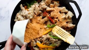 Adding the chicken fajita casserole seasoning to the cooked chicken and peppers.