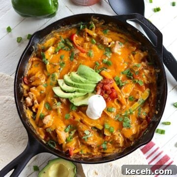 Baked chicken fajita casserole in a cast iron skillet with slices of avocado, sour cream, salsa, and fresh cilantro.