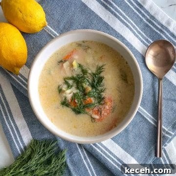 Authentic Greek Chickpea Soup (Revithosoupa) Recipe 13 A bowl of Greek Chickpea Soup garnished with dill sits on a blue and white linen with a spoon, fresh dill, and lemons.