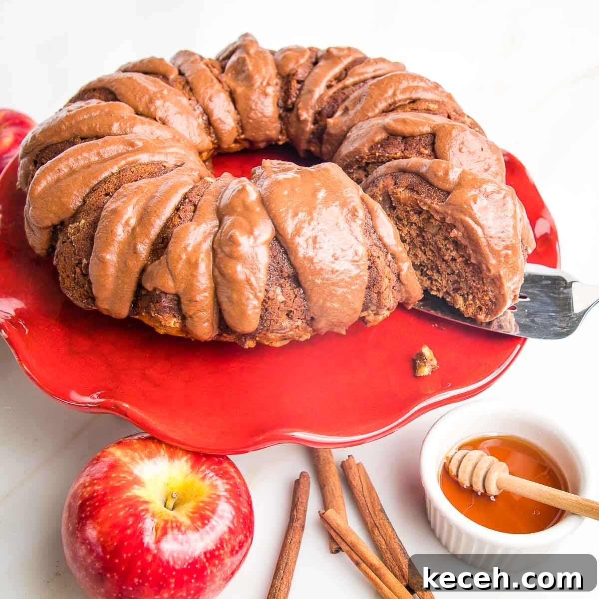 Apple bundt cake with chocolate drizzle on a red cake stand.