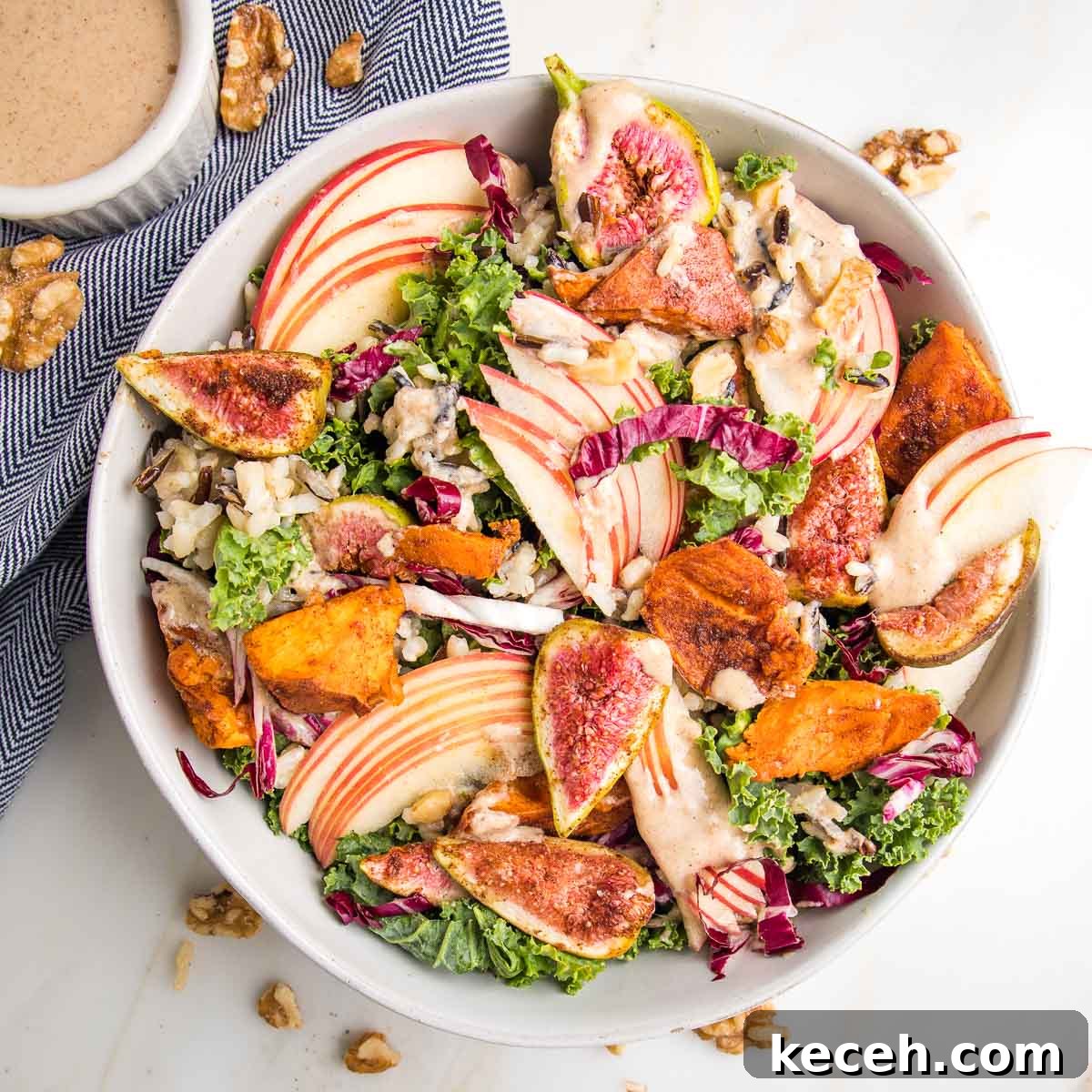 Large white bowl with kale and apple salad, roasted sweet potatoes and figs plus apple vinaigrette