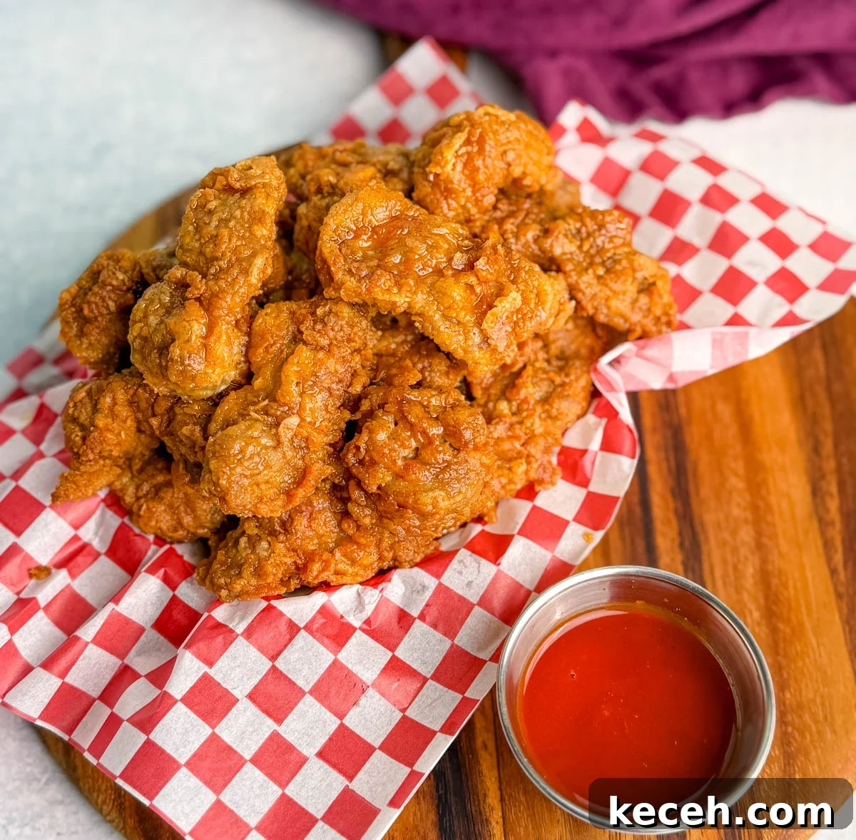 Crispy Fried Chicken Gizzards Recipe: Southern-Style Crunch 10 Basket of fried chicken gizzards on red and white checkered paper, served with a small cup of red dipping sauce.