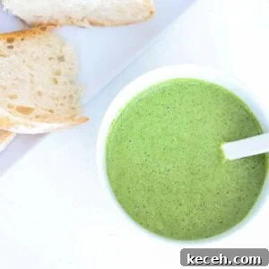 Pesto in a white bowl with a white spoon and a plate of sourdough to the top left of it.