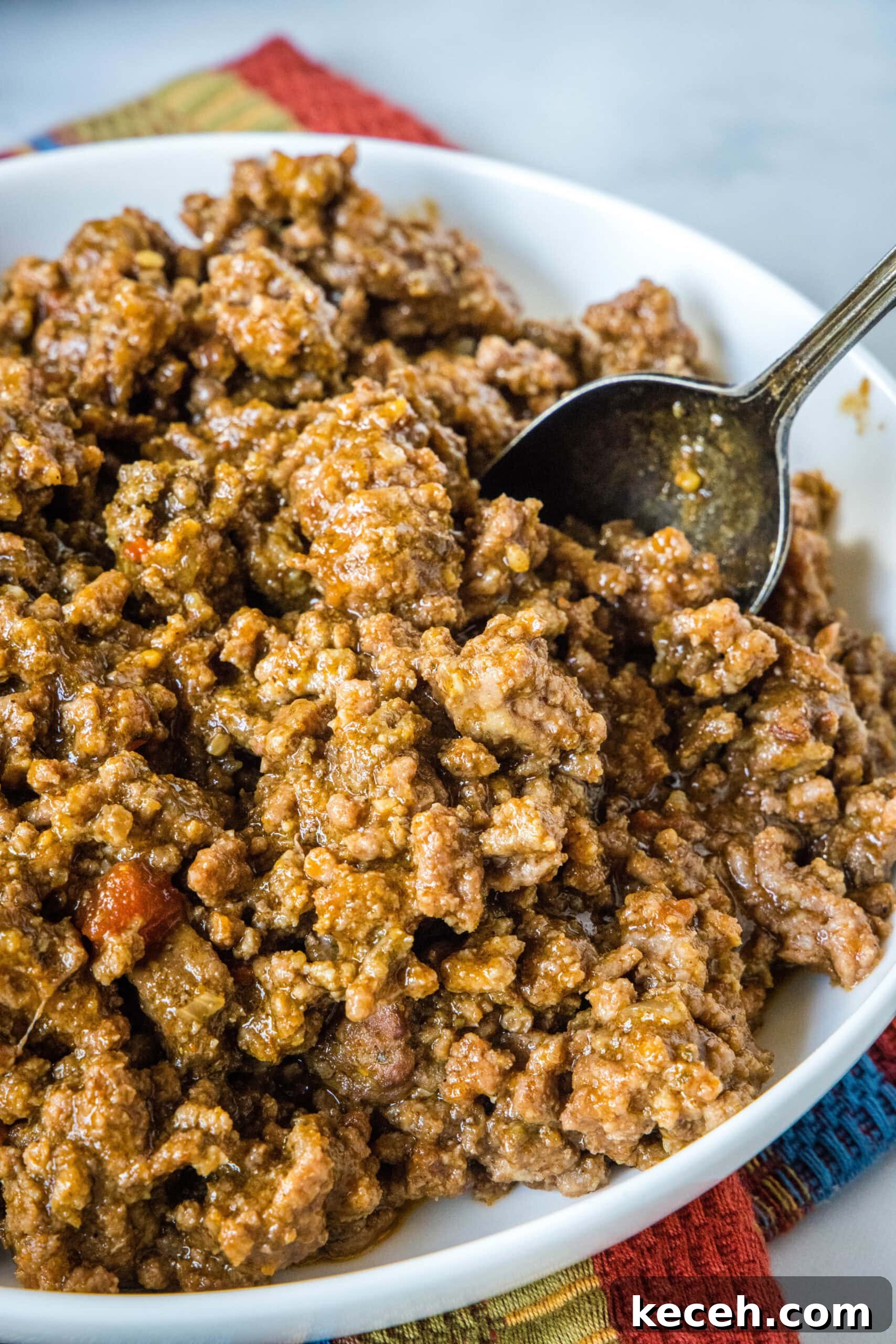 Slow cooker taco meat in a large white bowl with a spoon for serving.