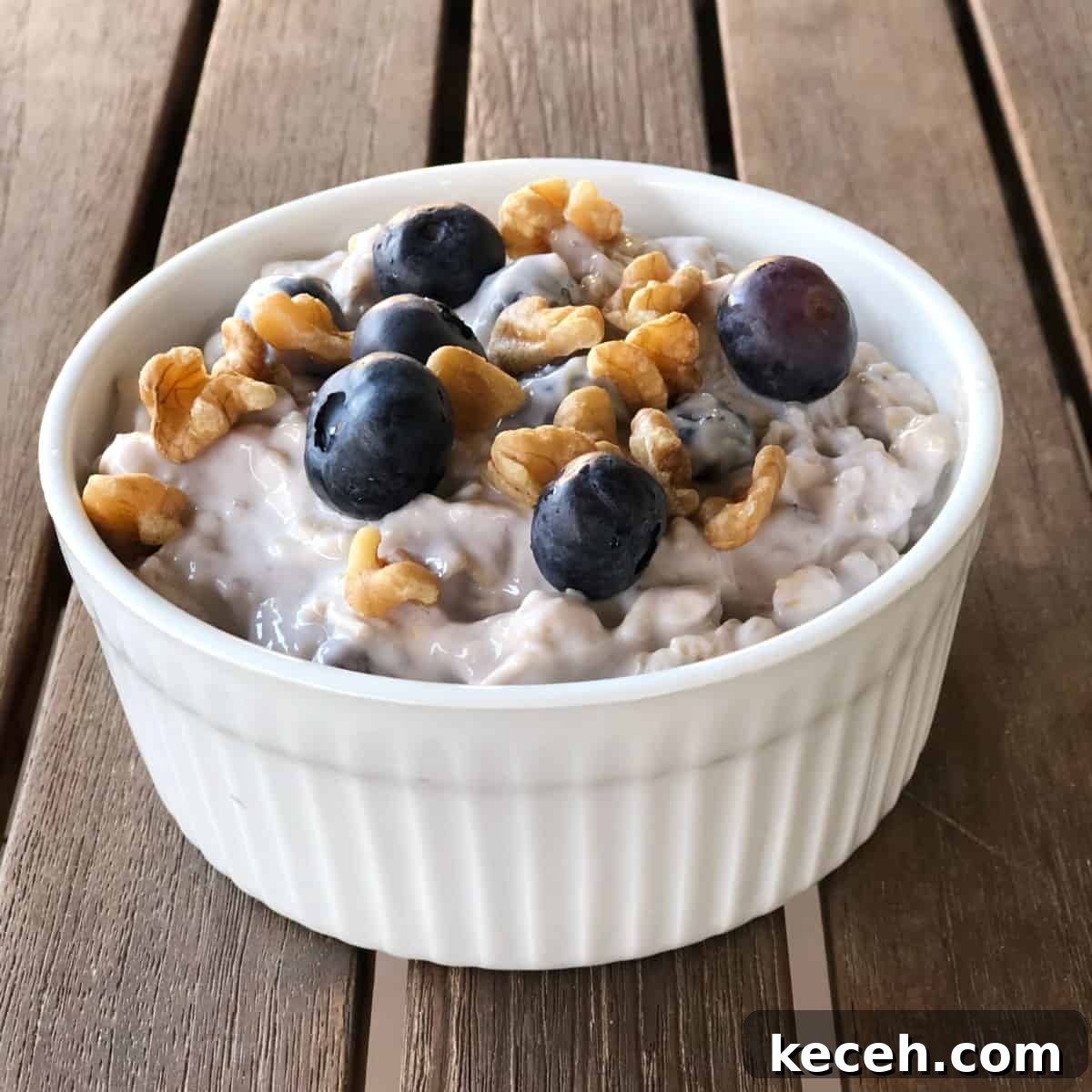 Blueberry and Maple Overnight Oats Recipe for Quick Breakfast 2 Blueberry maple overnight oats topped with toasted walnuts and fresh blueberries in small white ramekin.