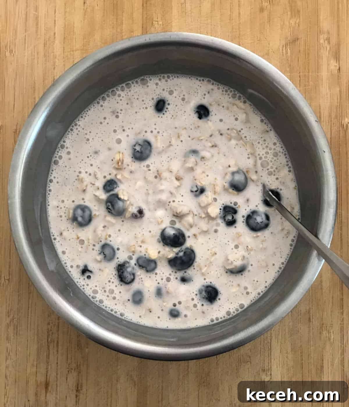 Blueberry and Maple Overnight Oats Recipe for Quick Breakfast 5 Stirring together milk, yogurt, oats and fresh blueberries in stainless steel mixing bowl.
