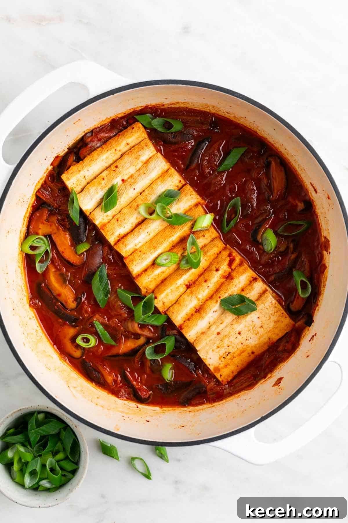 Vegan Kimchi Jjigae Recipe — Spicy Korean Kimchi Stew 2 Vegan kimchi stew in a large pot with scallions on top, and a bowl of extra scallions on the side.