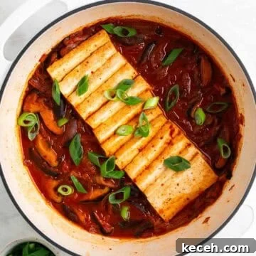 Vegan Kimchi Jjigae Recipe — Spicy Korean Kimchi Stew 12 Vegan kimchi stew in a large pot with scallions on top, and a bowl of extra scallions on the side.