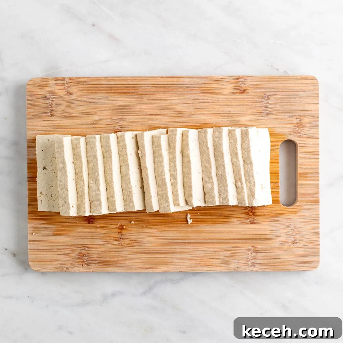 Vegan Kimchi Jjigae Recipe — Spicy Korean Kimchi Stew 7 Sliced tofu on a wooden cutting board.