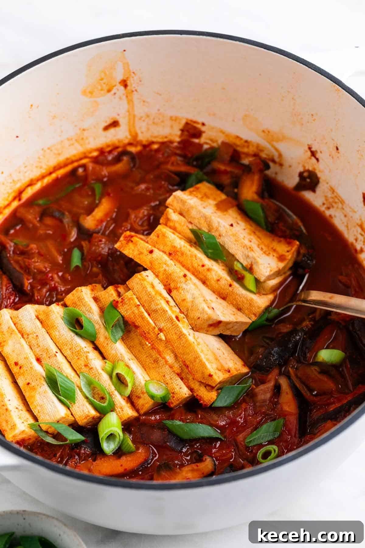 Vegan Kimchi Jjigae Recipe — Spicy Korean Kimchi Stew 10 Vegan kimchi stew in a large pot with scallions on top and a ladle inside.