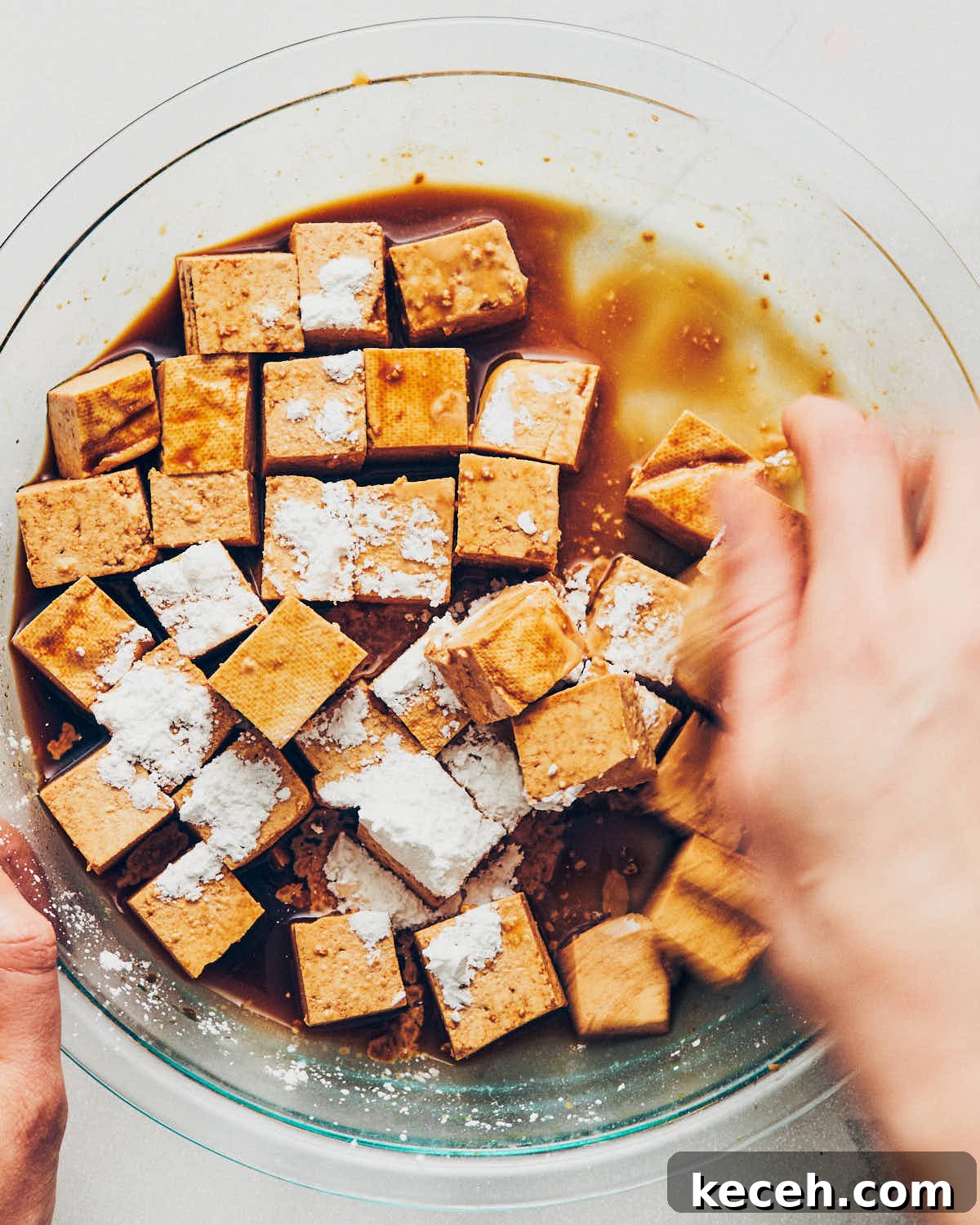 Crispy Air Fryer Breaded Tofu Recipe 10 Cornstarch sprinkled over tamari coated tofu, with a hand tossing to mix everything together