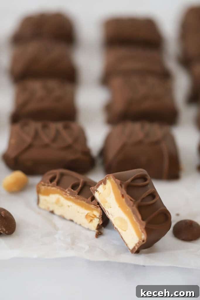 Snickers Candy: Flavor, Nutrition, and Serving Ideas 2 Mini homemade snickers candy bars on a baking sheet with one cut in half so you can see the layers.