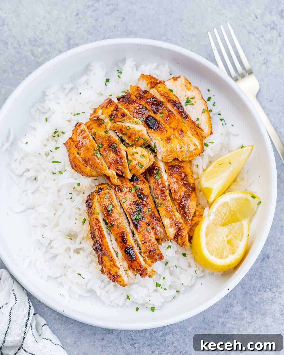 Crispy Air Fryer Boneless Chicken Thighs Recipe 2 Top view of a round white bowl with steamed white rice and sliced air-fried boneless chicken thighs.