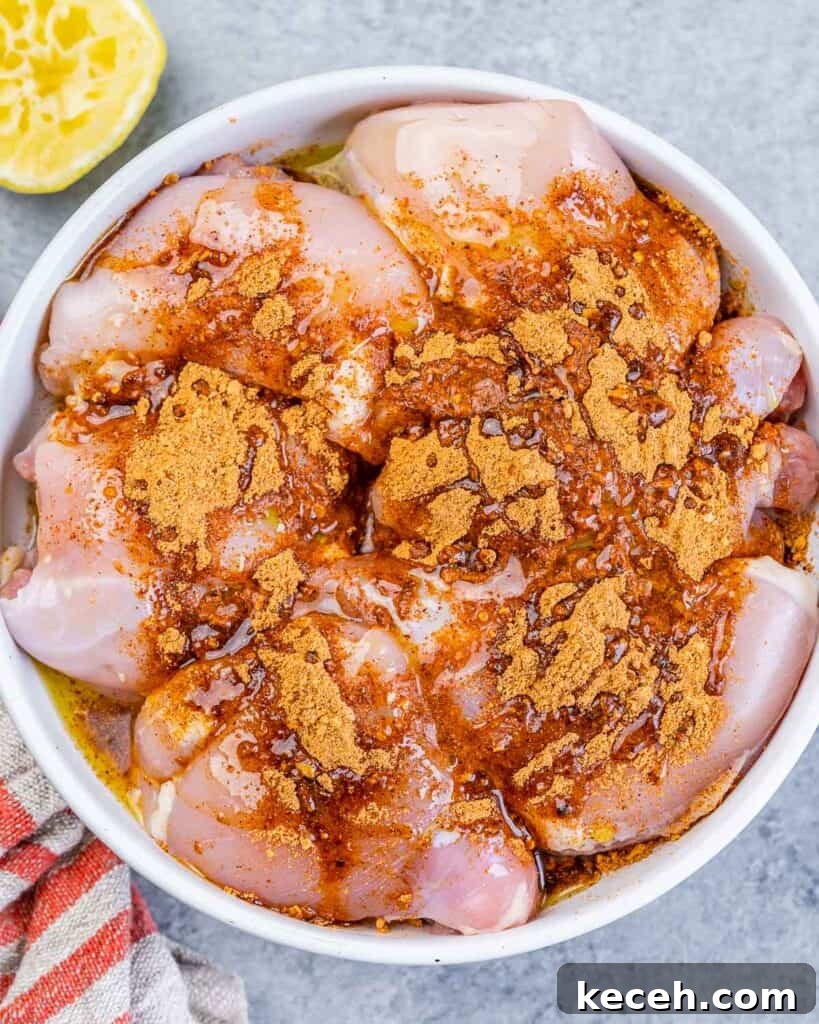 Crispy Air Fryer Boneless Chicken Thighs Recipe 5 Adding taco seasoning to raw chicken thighs in a bowl.