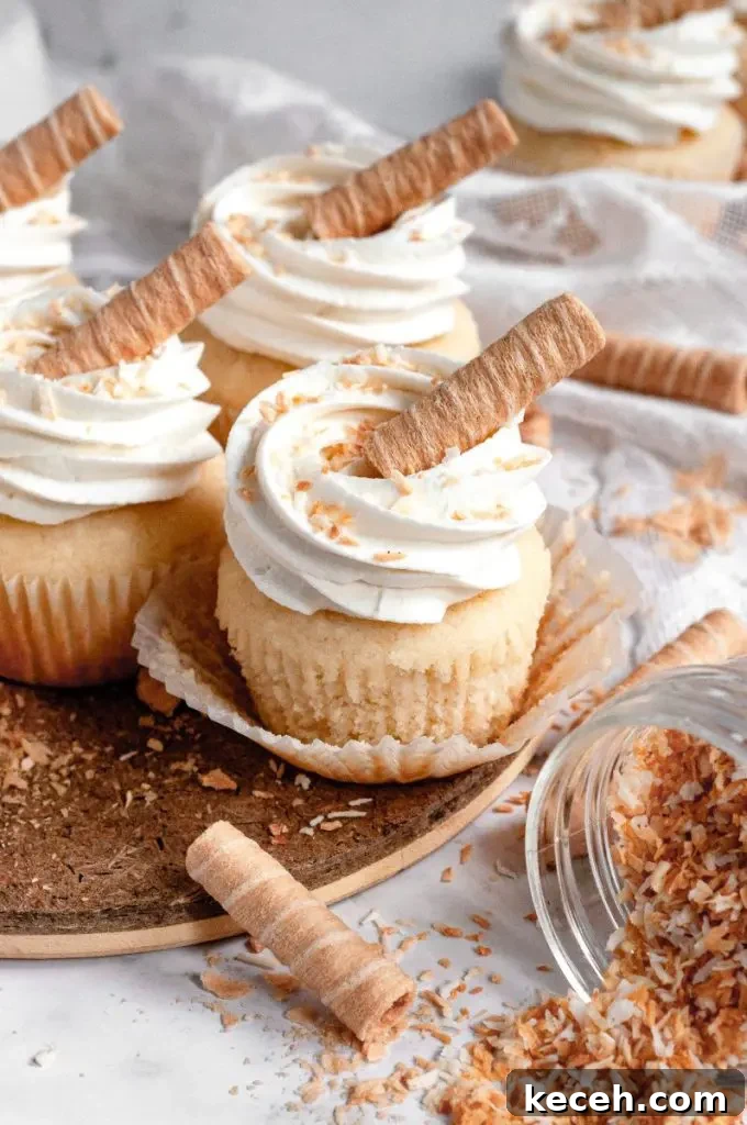 Gluten-Free Chocolate Raspberry Cupcakes with Vegan Option 9 Light golden coconut cupcakes topped with white whipped cream cheese frosting with some toasted coconut sprinkled on top.