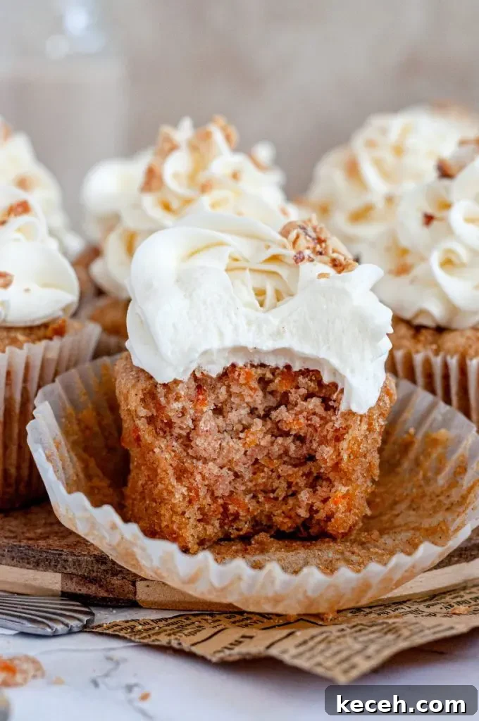 Gluten-Free Chocolate Raspberry Cupcakes with Vegan Option 10 An orange gluten-free carrot cake cupcake topped with white cream cheese frosting and chopped nuts. The cupcake liner is pulled down and there is a large bite taken out of the cupcake.