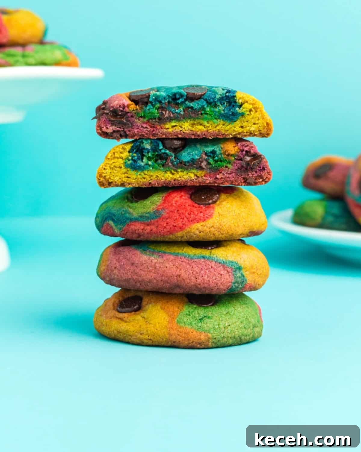 A stack of rainbow chocolate chip cookies against a neon blue background.