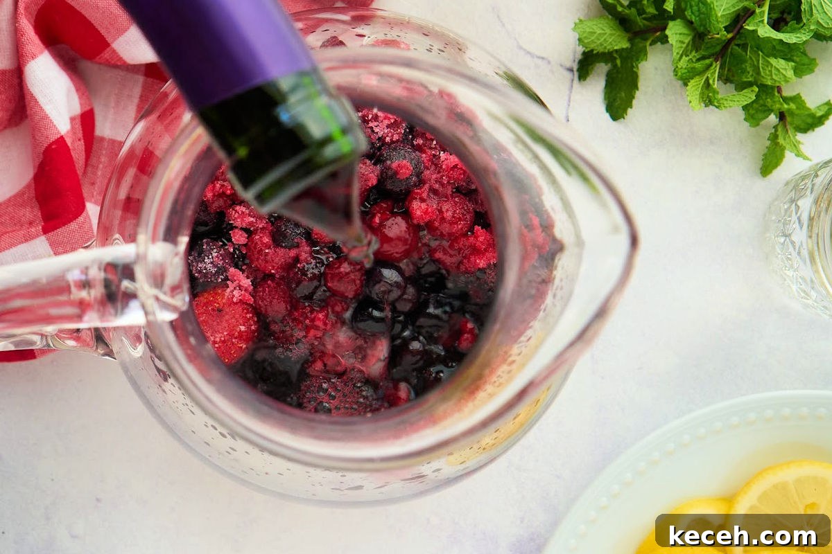 Triple Berry Sangria Recipe: Refreshing Summer Wine Punch 4 pitcher with wine being poured in.