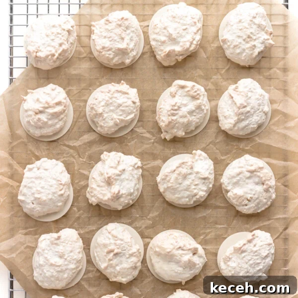 Snowman Chocolate Bark Recipe for Christmas Treats 15 Kokosmakronen (German Coconut Macaroons) on a piece of brown crumpled parchment paper set on top of a wire cooling rack.