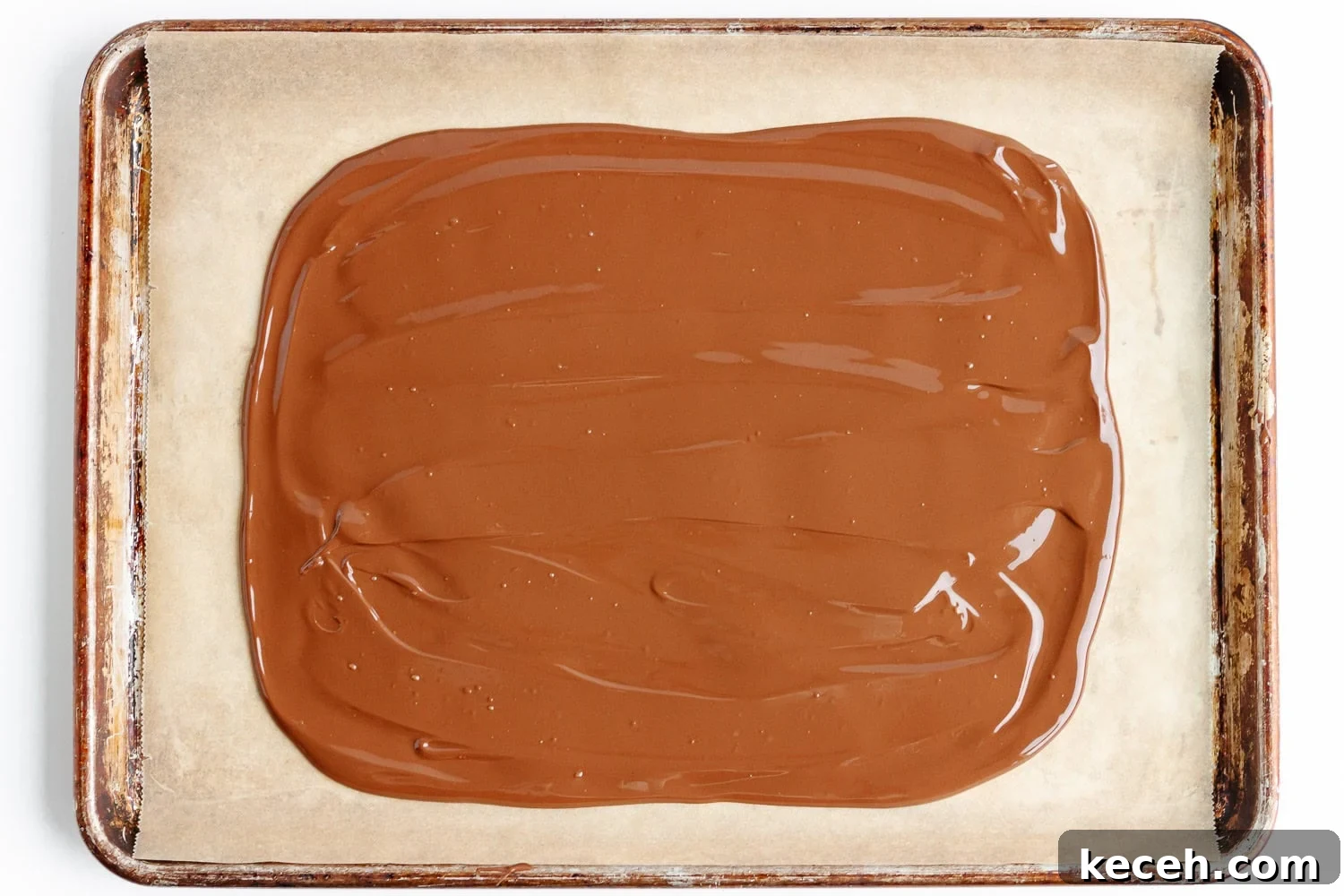 Snowman Chocolate Bark Recipe for Christmas Treats 6 Melted chocolate spread out into rectangular shape on parchment lined baking sheet.