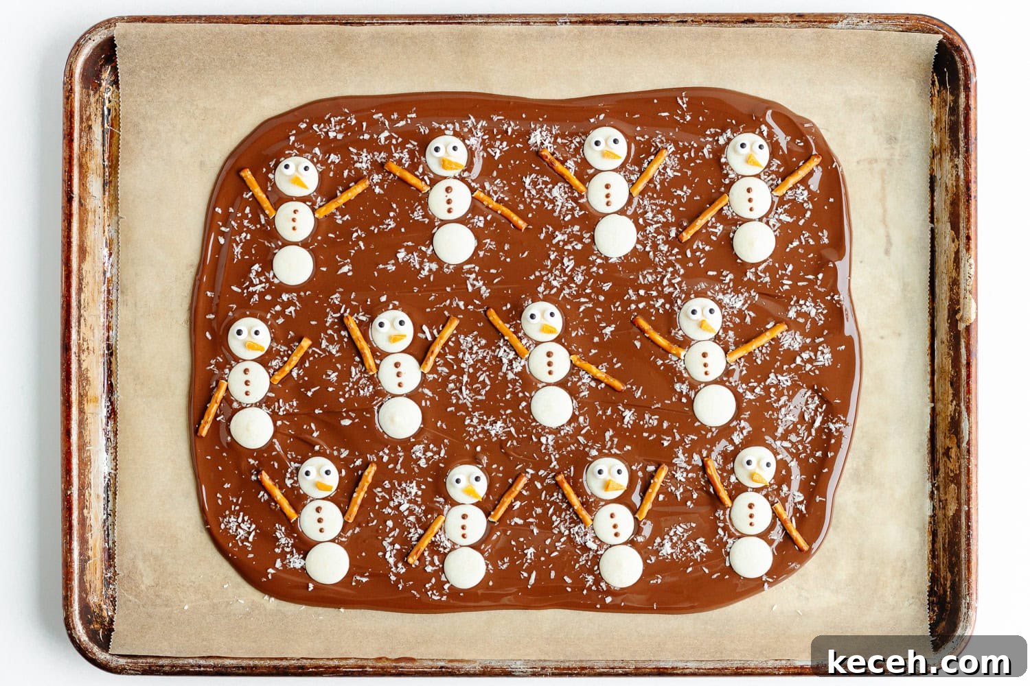Snowman Chocolate Bark Recipe for Christmas Treats 9 Finished snowmen assembled on chocolate bark on a parchment lined baking sheet.