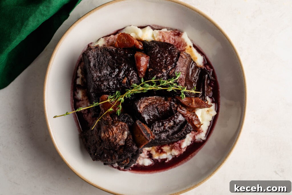 Red Wine Braised Beef Short Ribs with Rich Sauce 3 bowl of braised beef short ribs over a bed of mashed potatoes garnished with a sprig of thyme