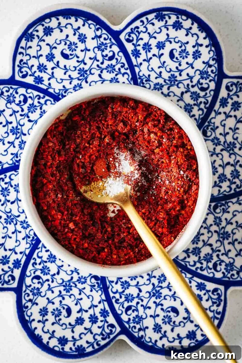 Top Substitutes for Aleppo Pepper: Flavorful Alternatives You Can Use 6 A small white bowl with golden teaspoon filled with chilli flakes and spices.