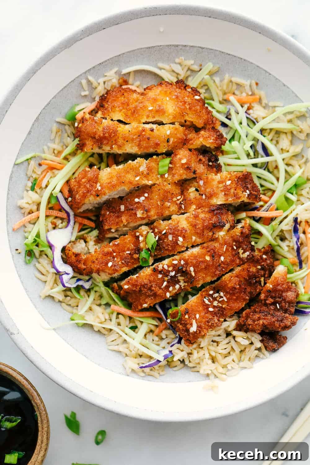 Awesome Chicken Katsu is a crispy breaded chicken breast seasoned and dipped in Panko then lightly fried in oil until the crust becomes a golden brown. A light and savory Japanese dish! Chicken Katsu chopped in slices and added over top cabbage and rice.