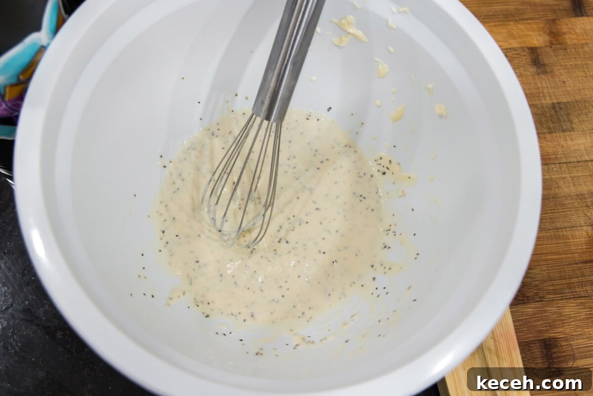 lobster salad dressing ingredients in a bowl with a whisk
